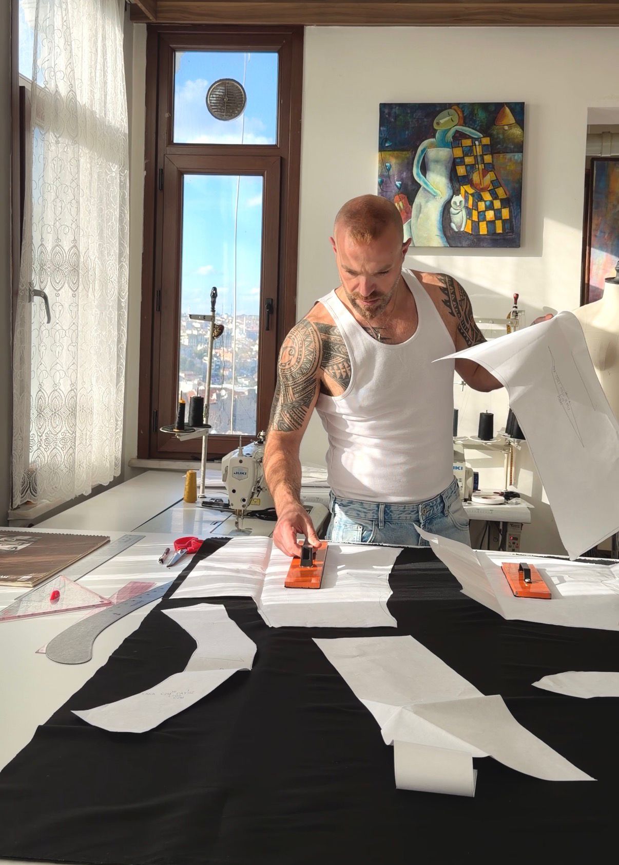 Designer working on a large black and white Dress Pattern making couture piece in a bright room with large windows.