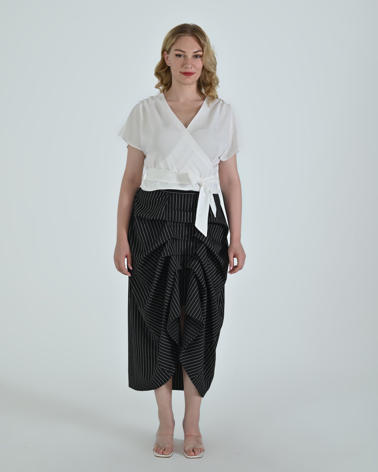 Black and white pinstripe high waisted sculptural skirt by Lumina Eligma
Architectural wool blend skirt with asymmetrical pleats
Designer black pinstripe skirt with modern tailoring
