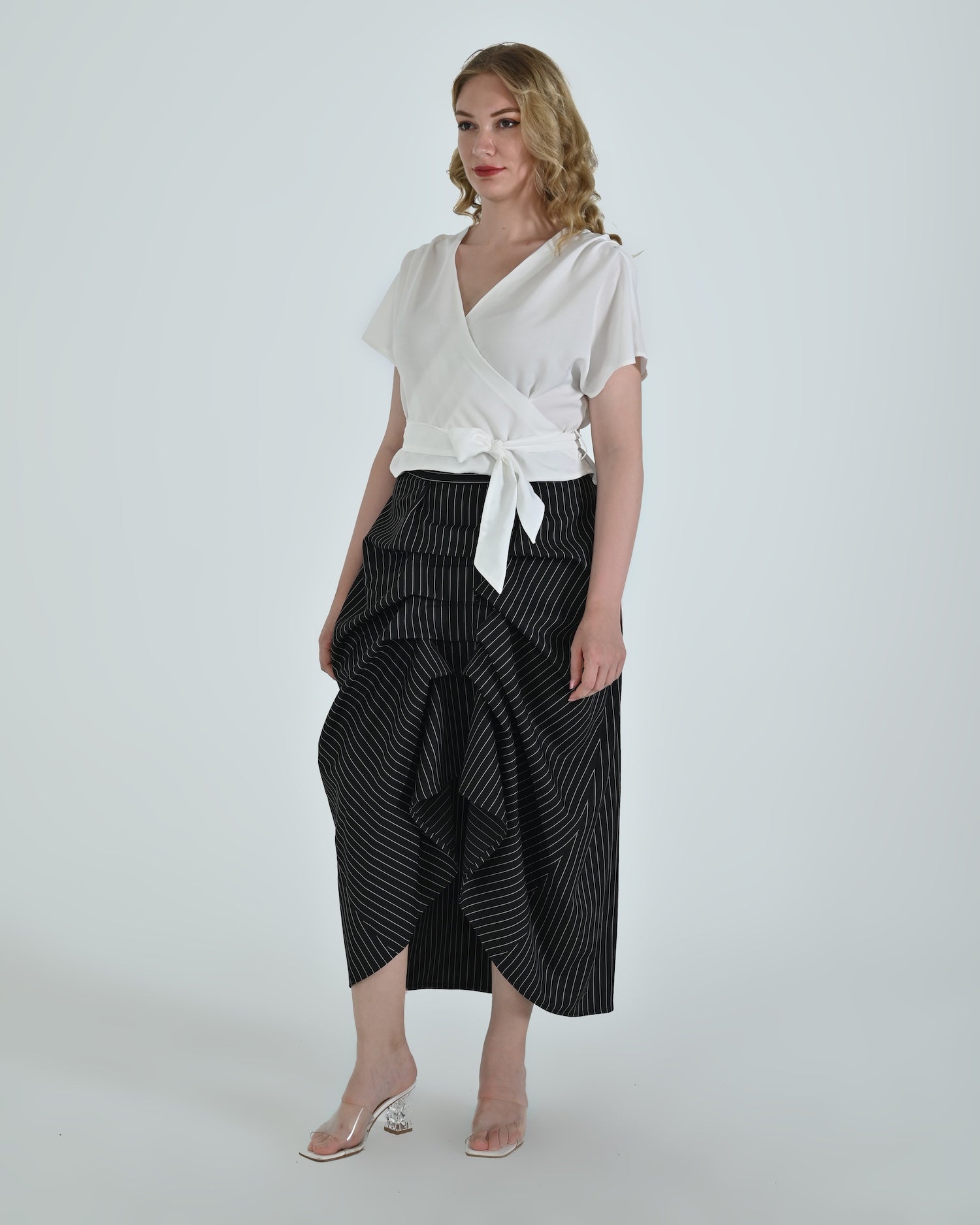 Black and white pinstripe high waisted sculptural skirt by Lumina Eligma
Architectural wool blend skirt with asymmetrical pleats
Designer black pinstripe skirt with modern tailoring
