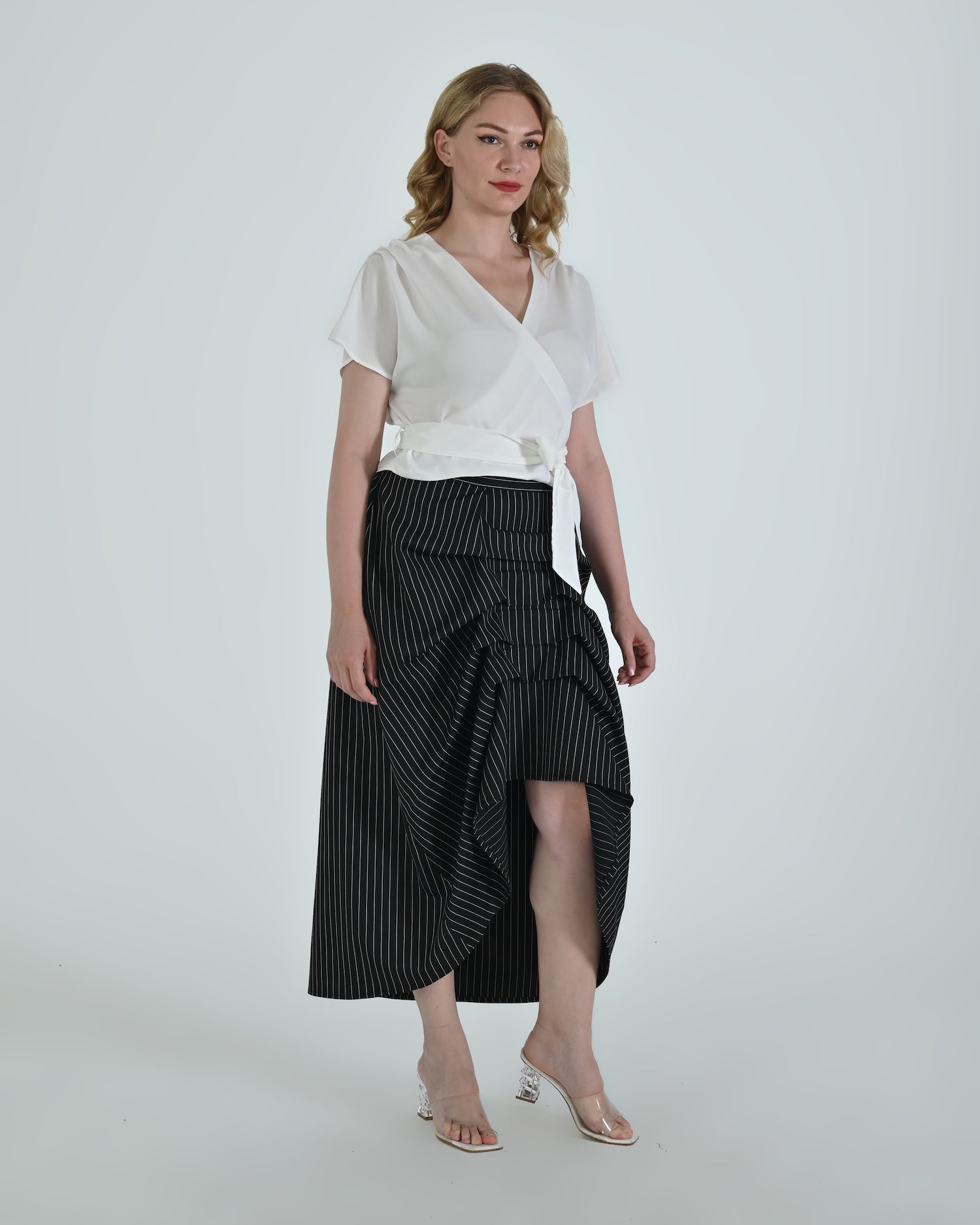 Black and white pinstripe high waisted sculptural skirt by Lumina Eligma
Architectural wool blend skirt with asymmetrical pleats
Designer black pinstripe skirt with modern tailoring
