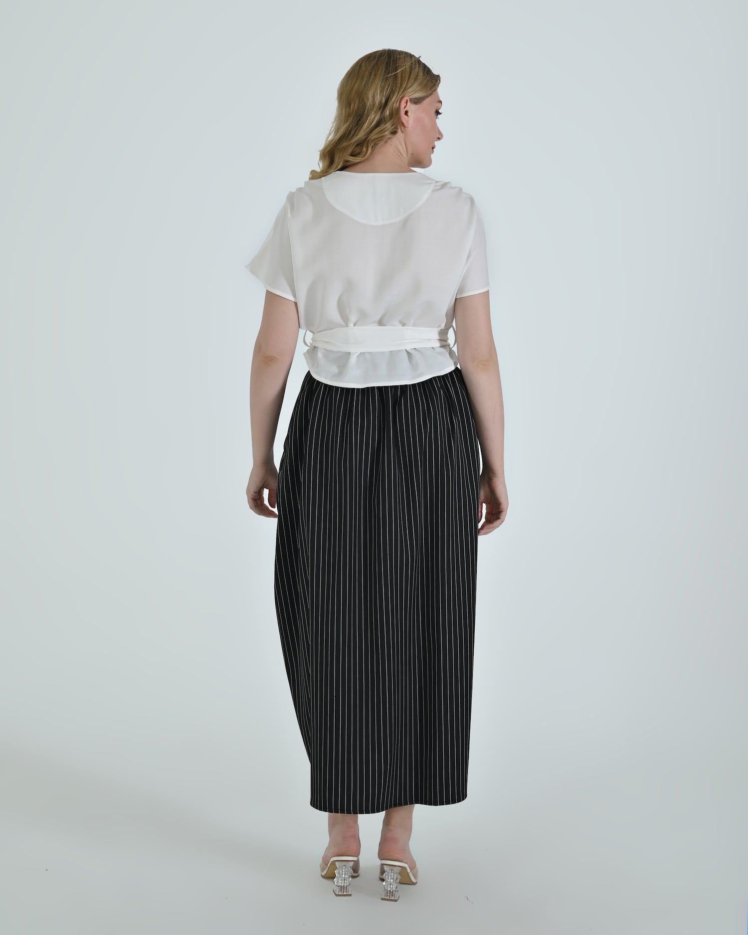 Black and white pinstripe high waisted sculptural skirt by Lumina Eligma
Architectural wool blend skirt with asymmetrical pleats
Designer black pinstripe skirt with modern tailoring
